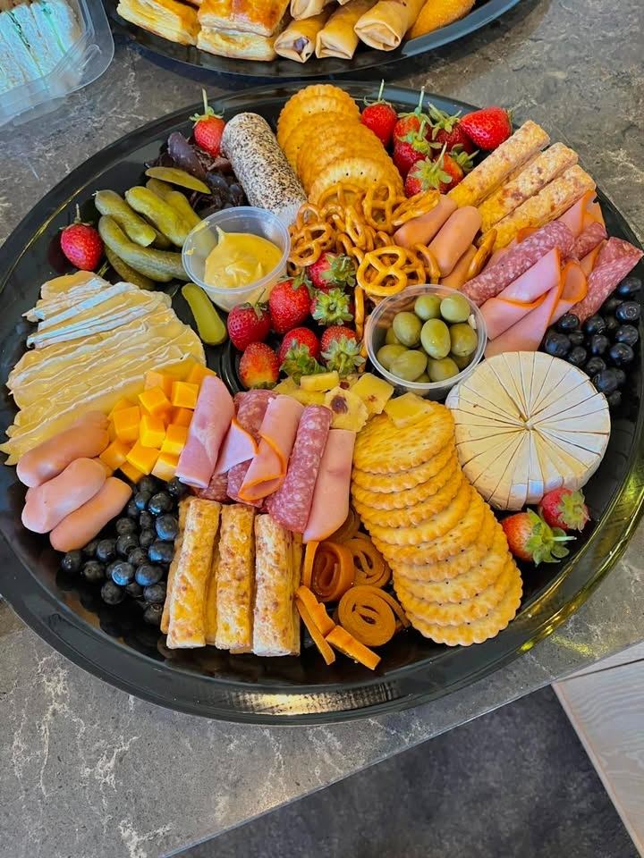 Grazing platter with cold meats, cheeses, crackers, olives, pickles, strawberries and blueberries